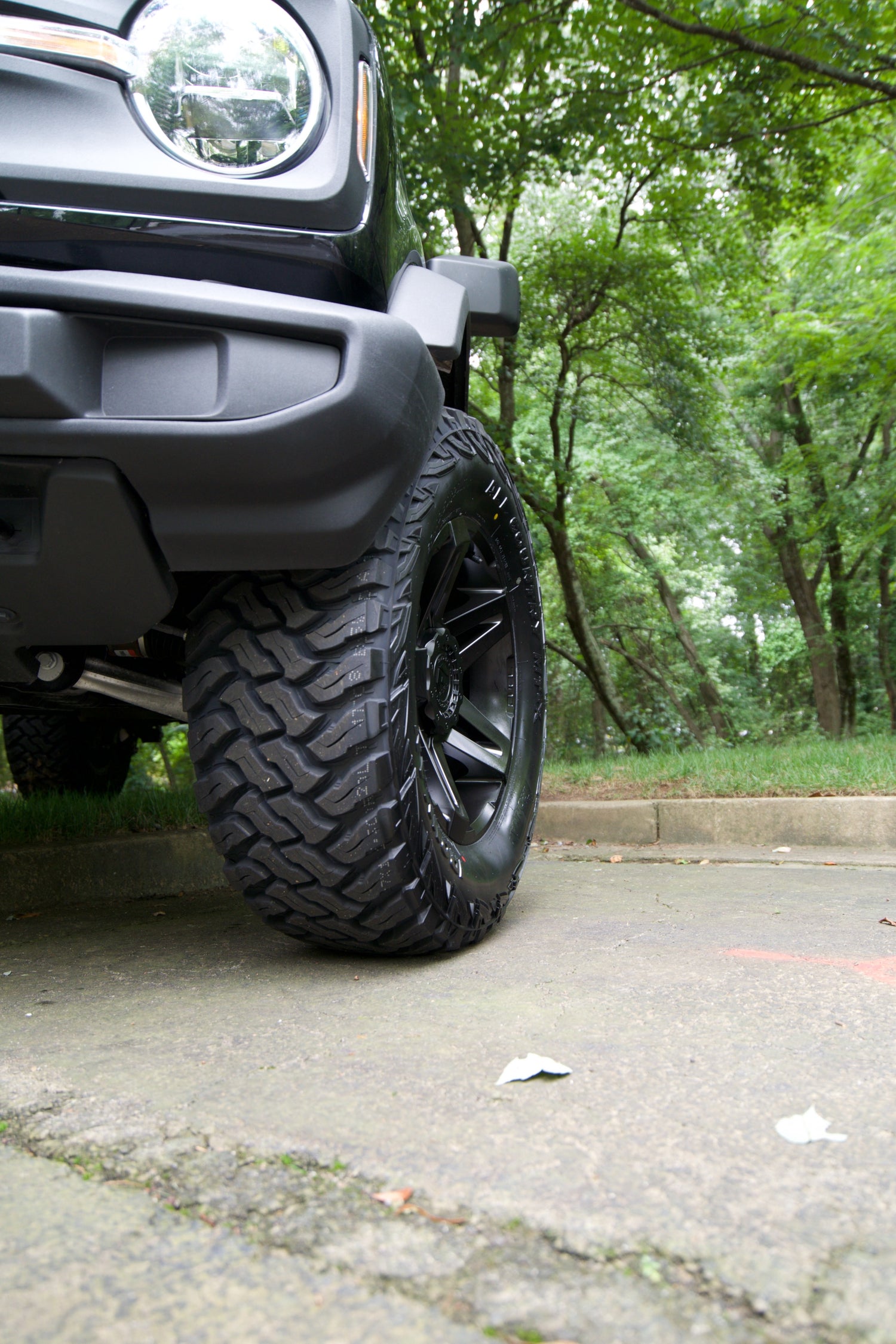 Close-up of a vehicle tire with a forest background